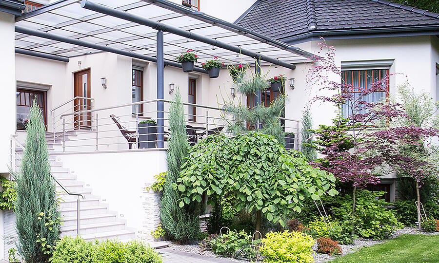 Image of a home with plants, steps, a glass awning, and rocks in the landscaping because sometimes mulch won't cut it