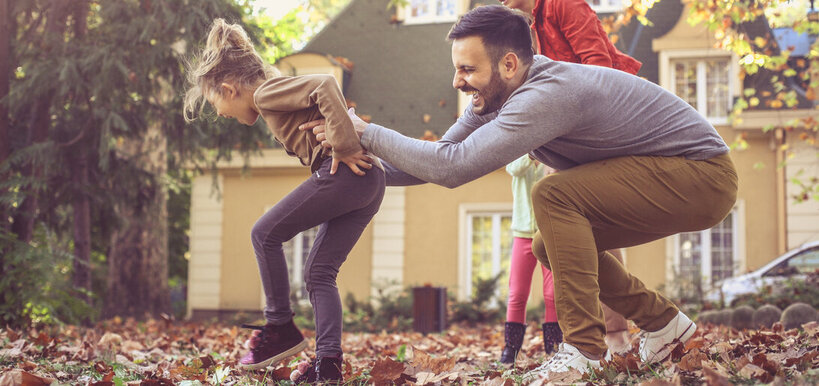 happy family playing in the Fall leaves after buying a home