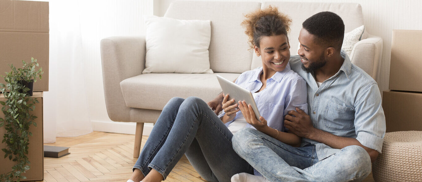 Couple Using Tablet Computer Sitting On Floor Indoor