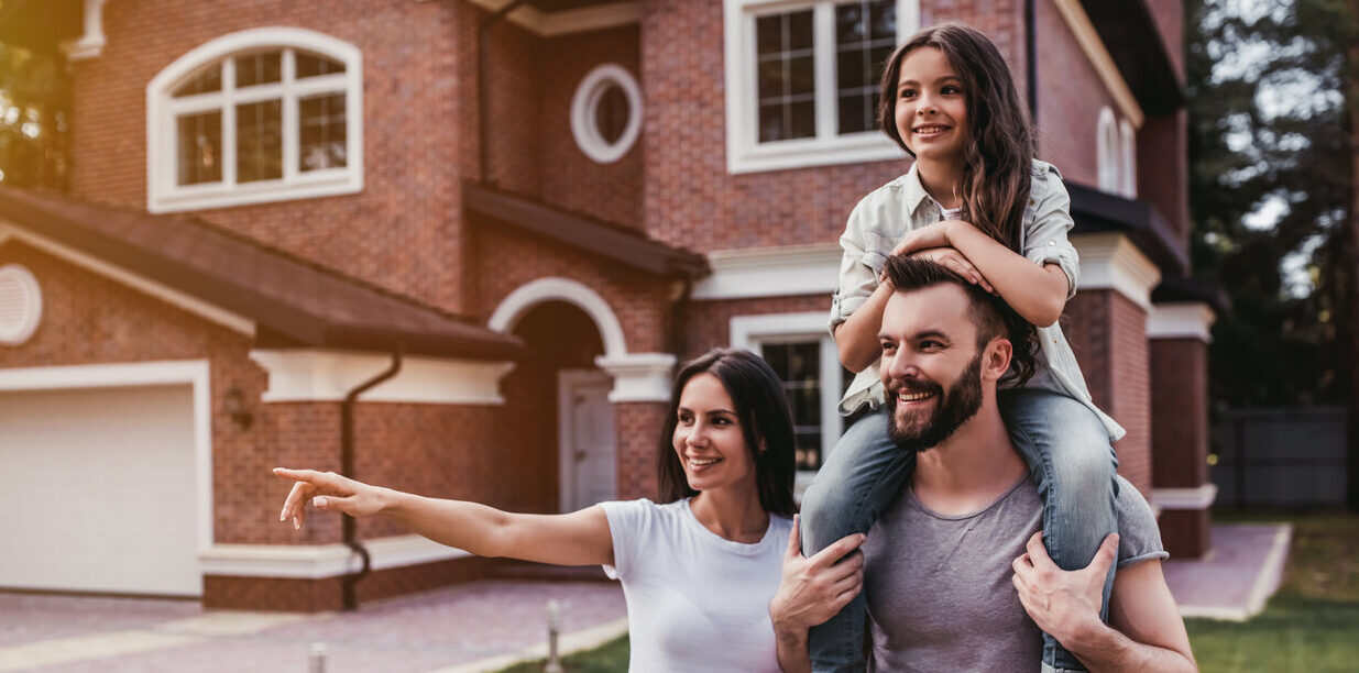 Happy family is standing near their modern house which they got using an adjustable-rate mortgage