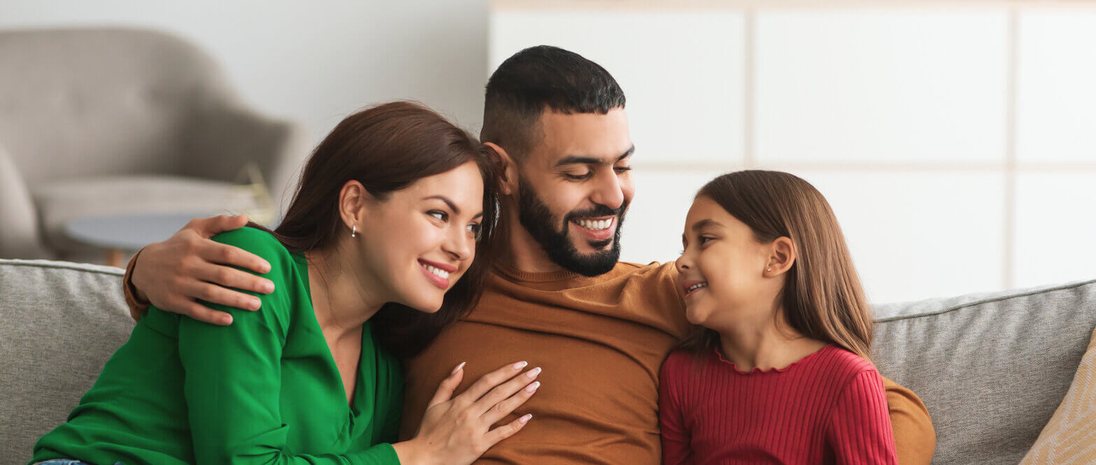 family sitting on couch celebrating after getting a home with a VA Loan